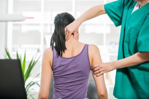 Photo of a Chiropractor adjusting neck muscles on female patient